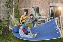 Famiglia felice che gioca in amaca nel giardino della loro casa — Foto stock
