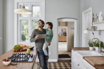 Father and son using tablet in kitchen looking at ceiling lamp — Stock Photo
