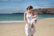 Мать держит маленькую дочь на пляже — стоковое фото