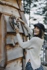 Щаслива молода жінка прикрашаючи дерев'яний будинок з прикрасою Різдва — стокове фото