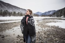 Молода жінка взимку стоїть біля річки. — стокове фото
