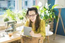 Retrato de designer de moda sorridente sentado em seu estúdio usando tablet — Fotografia de Stock