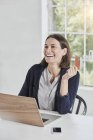 Смеющаяся деловая женщина с ноутбуком на столе с карточкой — стоковое фото
