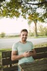 Ritratto di uomo sorridente con cellulare all'aperto — Foto stock