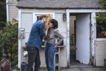 Hombre con máscara divertida y besar a la mujer en casa - foto de stock