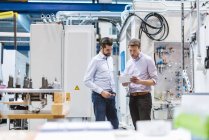 Due uomini in fabbrica a guardare tablet — Foto stock