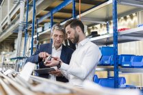 Бізнесмени під час зустрічі з планшетом і продуктом у виробничому залі — стокове фото