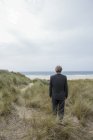 UK, Cornwall, Hayle, businessman standing in beach dunes and looking at view — Stock Photo