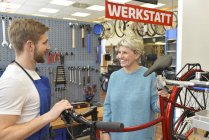 Vendedor ayudando al cliente en tienda de bicicletas - foto de stock