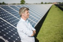 Sonriente hombre maduro de pie en planta solar - foto de stock