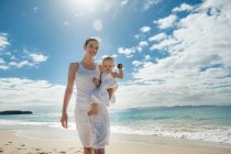 Madre caminando con su hijita en la playa - foto de stock