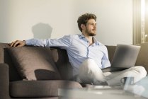 Mann sitzt zu Hause mit Laptop auf Couch — Stockfoto
