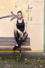 Donna sportiva con borraccia seduta su panchina — Foto stock