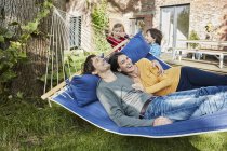 Glückliche Familie spielt in Hängematte im Garten ihres Hauses — Stockfoto