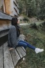 Giovane donna seduta in una casa di legno nella natura — Foto stock