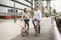Couple souriant à vélo dans la ville — Photo de stock