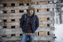 Uomo in piedi di fronte a mucchio di legno all'aperto in inverno — Foto stock