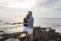 Cariñosa pareja de ancianos abrazándose en el mar - foto de stock