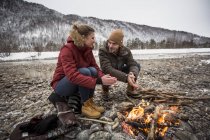 Coppia su un viaggio in mani scaldanti invernali a fuoco di campo — Foto stock