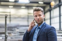 Портрет впевненого бізнесмена на мобільному телефоні на заводі — стокове фото