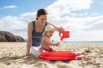 Madre che gioca con la piccola figlia sulla spiaggia — Foto stock