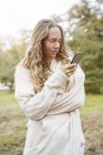 Mujer rubia en el paisaje rural mirando el teléfono celular - foto de stock