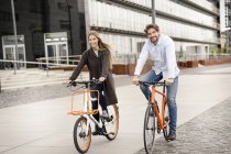 Усміхнена пара їде на велосипеді в місті — стокове фото