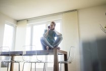 Businesswoman on the phone sitting barefoot on meeting table — Stock Photo