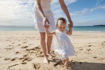 Mutter hilft kleiner Tochter am Strand — Stockfoto