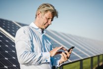 Empresario usando smartphone en el parque solar - foto de stock