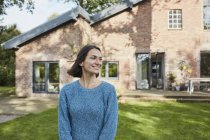 Donna sorridente nel giardino della sua casa — Foto stock