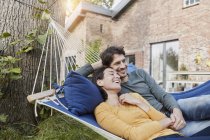 Happy couple lying in hammock in garden of their home — Stock Photo