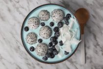 Ciotola di frullato blu con cocco grattugiato, mirtilli e palline di frutta del drago — Foto stock