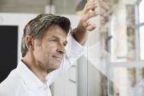 Portrait d'un homme d'affaires mature appuyé contre un mur de verre au bureau — Photo de stock