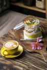 Muesli exótico con flor y taza de café en una mesa de madera - foto de stock
