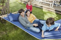 Famiglia felice che gioca in amaca nel giardino della loro casa — Foto stock