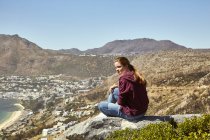 South Africa, Cape Town, young woman sitting at coast looking at view — Stock Photo