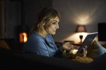 Portrait of smiling woman using tablet at home in evening — Stock Photo