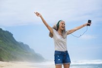 Donna anziana con cuffie che ballano sulla spiaggia — Foto stock