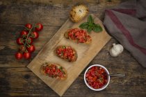 Bruschetta with tomatoes and basil on wooden board — Stock Photo