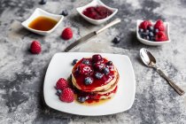 Pancakes with red fruit jelly, maple sirup, raspberries and blueberries — Stock Photo