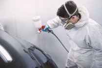 Auto painter painting a car inside a paint booth — Stock Photo
