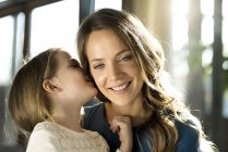Sorridente ragazza sussurrando nell'orecchio di sua madre — Foto stock