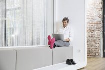 Empresario con calcetines rosados usando portátil en la oficina - foto de stock