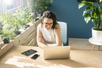 Lächelnder Freiberufler sitzt am Schreibtisch im Loft und schaut auf Laptop — Stockfoto