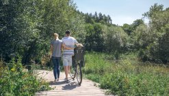 Семья с велосипедом ходить по деревянной дорожке — стоковое фото