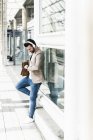 Молода людина в навушниках чекає на платформі станції — стокове фото
