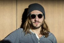 Retrato de homem barbudo com cabelos longos usando óculos de sol e chapéu de lã — Fotografia de Stock