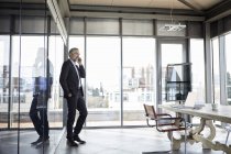 Uomo d'affari in piedi in ufficio a parlare sul cellulare pohone — Foto stock