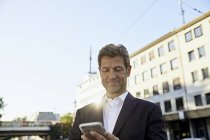 Uomo d'affari maturo utilizzando smartphone in città — Foto stock